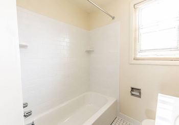 a bathroom with a white bathtub and a window